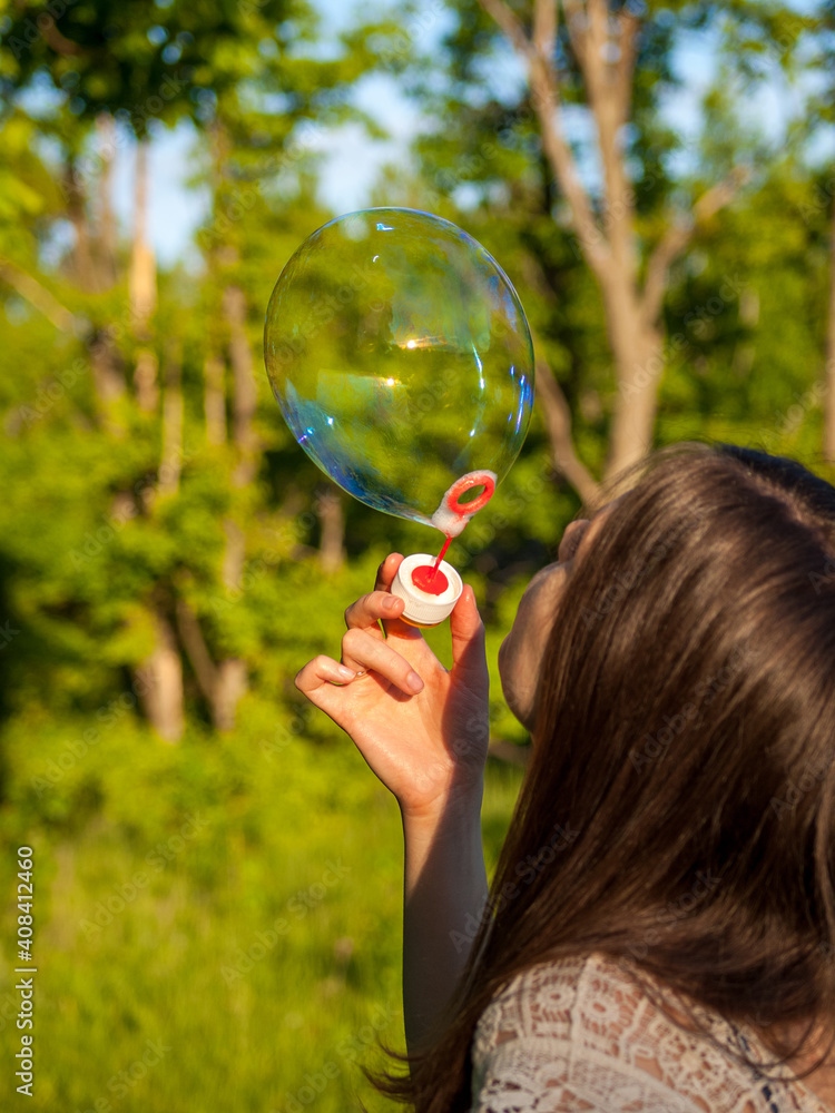 young girl inflates soap bubbles in summer in sunny weather, outdoor recreation, big soap bubbles young girl inflates soap bubbles in summer in sunny weather, outdoor recreation, big soap bubbles