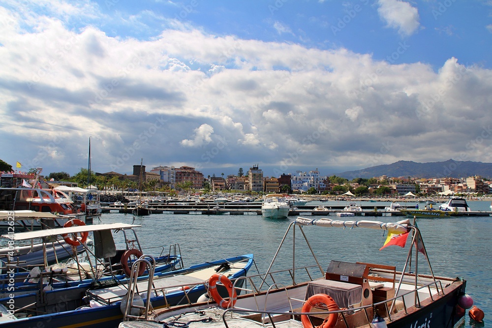 mountain view over the sea, above them a lot of dense white clouds, mountains descending into the sea, boats at sea, Sicily, a bay with moored barges and boats