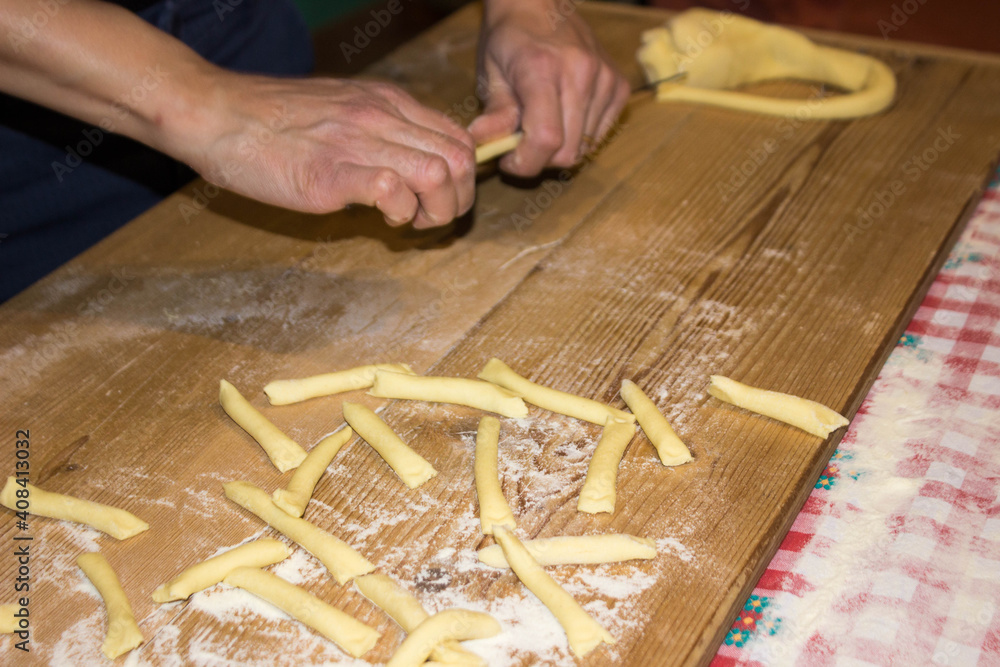 italian woman making pasta in the kitchen on wooden table on background. Female hands. Concept of homemade food.