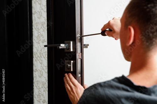 man repairing the doorknob. Carpenter working on lock installation with out the door knobs wood door