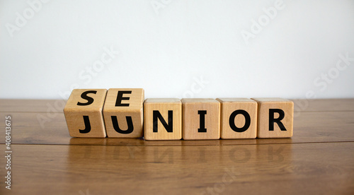 From junior to senior symbol. Turned cubes and changed the word 'junior' to 'senior'. Beautiful wooden table, white background, copy space. Business and junior or senior concept. photo