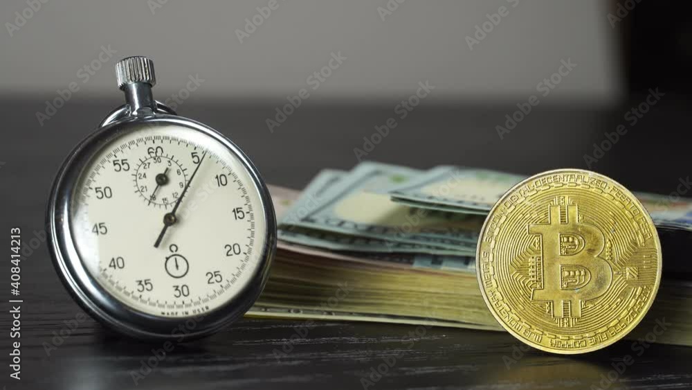 Bitcoin BTC with stopwatch lies on dollars bills. Time is money concept. Currency or cash revenue. Cryptocurrency or trade concept. Record high boosted by increased demand from retail investors Bitcoin BTC with stopwatch lies on dollars bills. Time is money concept. Currency or cash revenue. Cryptocurrency or trade concept. Record high boosted by increased demand from retail investors