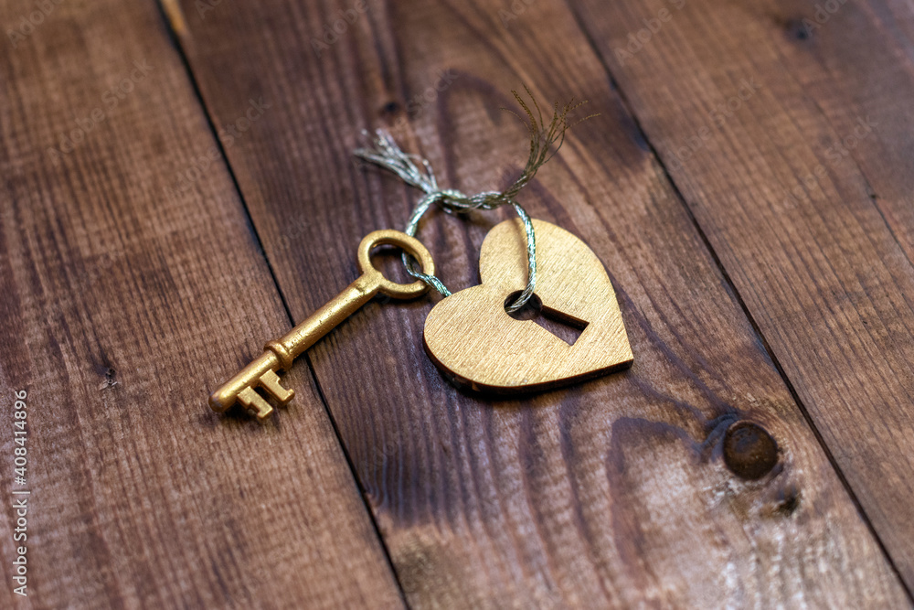 Top view shot of gold heart and key on wood background with copy space Top view shot of gold heart and key on wood background with copy space