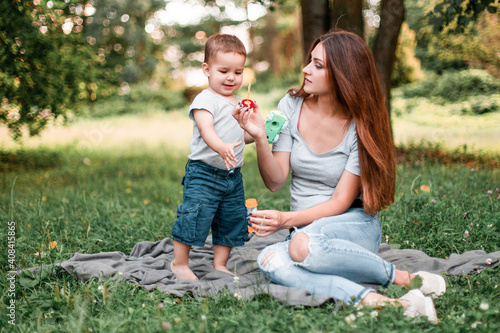  Mother with son blowing soap bubbles in the park. © zadorozhna