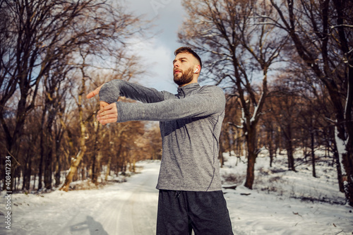 Sportsman standing in nature and doing warm up exercises at snowy winter day. Winter sport, snowy weather, warm up exercises © dusanpetkovic1