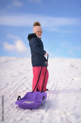 Little girl enjoying a sleigh ride. Child sledding.