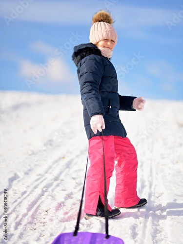 Little girl enjoying a sleigh ride. Child sledding.