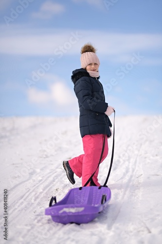 Little girl enjoying a sleigh ride. Child sledding.