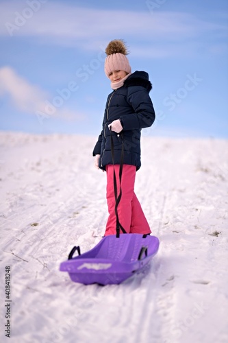 Little girl enjoying a sleigh ride. Child sledding.