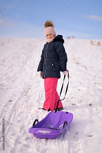 Little girl enjoying a sleigh ride. Child sledding.