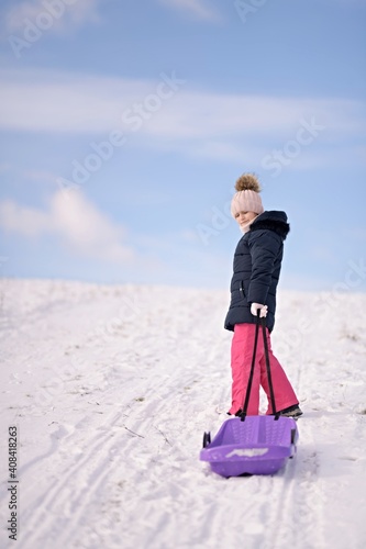 Little girl enjoying a sleigh ride. Child sledding.