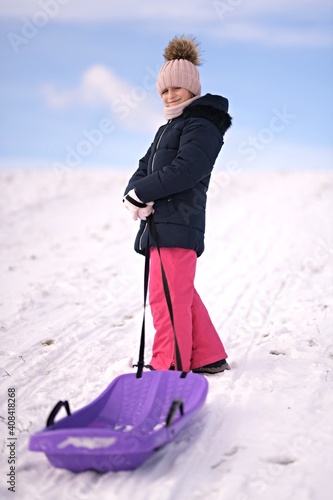 Little girl enjoying a sleigh ride. Child sledding.