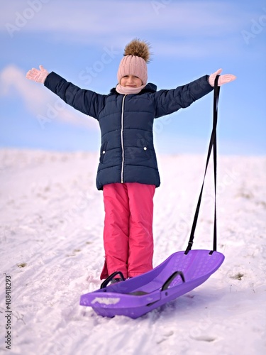 Little girl enjoying a sleigh ride. Child sledding.