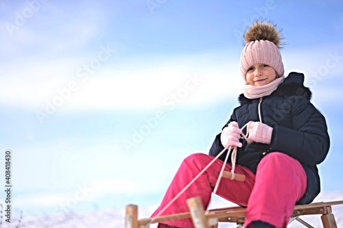 Little girl enjoying a sleigh ride. Child sledding.