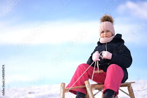 Little girl enjoying a sleigh ride. Child sledding.