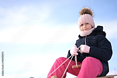 Little girl enjoying a sleigh ride. Child sledding.