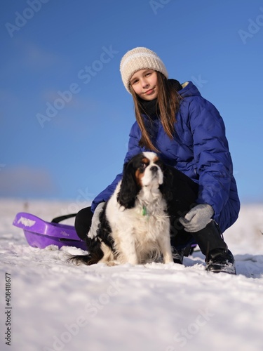 Fototapeta Naklejka Na Ścianę i Meble -  Attractive young woman having fun outside in snow with her dog puppy