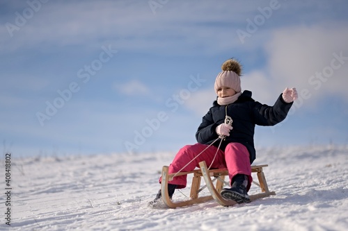 Little girl enjoying a sleigh ride. Child sledding.