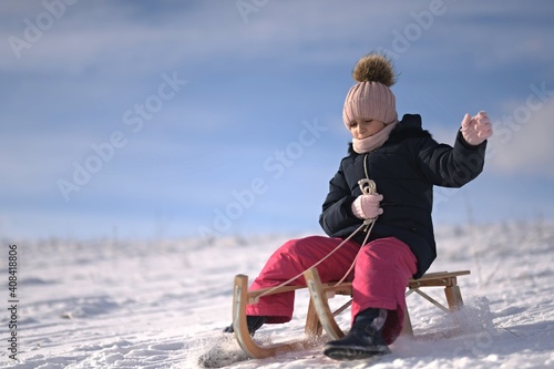 Little girl enjoying a sleigh ride. Child sledding.