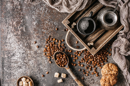 Coffee beans with coffee and cookie on dark textured background.