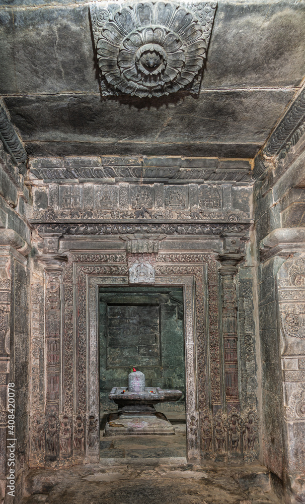 Lakkundi, Karnataka, India - November 6, 2013: Kasivisvesvara Temple. Looking through door into inner sanctum upon Shivalingam standing in Yoni. Gray stone walls, floor, and ceiling.