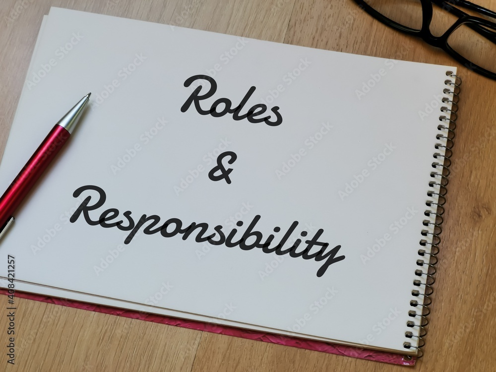 Text Roles and Responsibility on note book with pen and eye glasses on wooden table. Text Roles and Responsibility on note book with pen and eye glasses on wooden table.