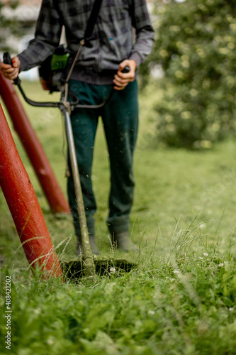 The head of a gasoline manual lawnmower while working against the background of freshly mown grass.