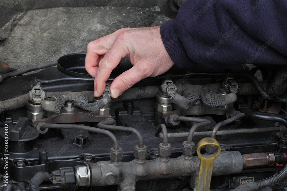 Worker fixing modern common rail diesel engine, closeup of hand placing electrical connector to injector Worker fixing modern common rail diesel engine, closeup of hand placing electrical connector to injector