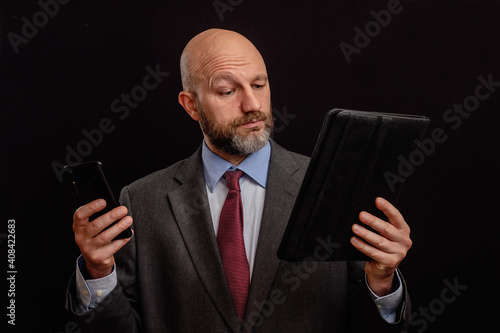 Bald business man in his 40s in classic grey suit on dark background. Sigh exhaustion on his face, bags under his eyes, strong lines on his forehead. Stress at work and worn out concept