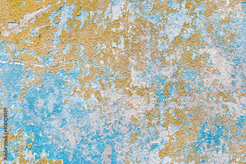 The texture of the old peeling paint from the dirty color concrete wall background of an abandoned house
