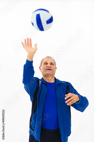 Portrait of an elderly man in a blue tracksuit playing with a ball against a white background