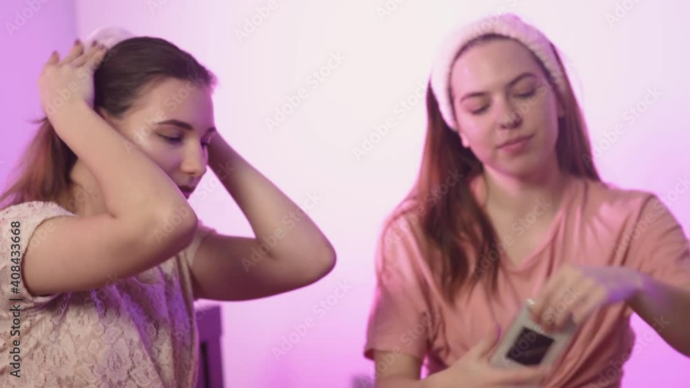 Happy pretty young women in pajamas sits on bed and puts on headbands at bachelorette party Happy pretty young women in pajamas sits on bed and puts on headbands at bachelorette party