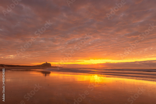 Stunning winters sunrise over Nobbys Beach. Nobbys Lighthouse in the distance. Newcastle, Hunter Region of N.S.W. Australia.