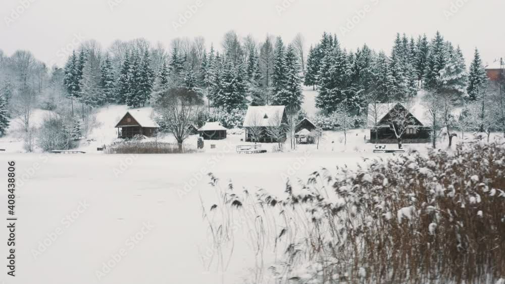 Slow drone flight over frozen Lake with a lot of snow on it. Snow, Lake, trees, houses visible. Cloudy day. Slow drone flight over frozen Lake with a lot of snow on it. Snow, Lake, trees, houses visible. Cloudy day.