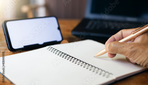 Close-up of hands. businessman writing plan on book while meeting with mobile phone at home