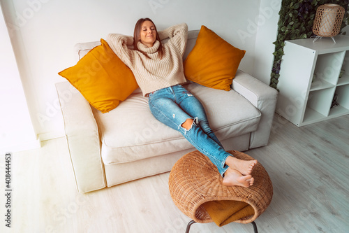 Calm satisfied woman relaxing or sleeping on the sofa in living room. Carefree lady resting at home, enjoying stress free weekend. Day off work. Home lifestyle, home comfort concept. 