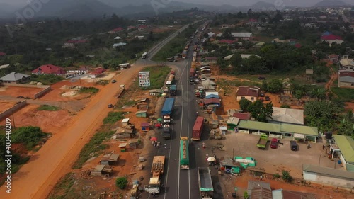 Aerial busy truck traffic rural village Ghana Africa 4K. Busy congested market area and truck parking in rural village. Survive in low income poverty of Africa. Vehicles roadside market shops.