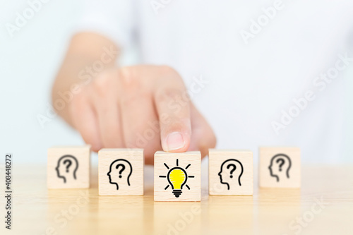 Concept creative idea and innovation. Hand choose wooden cube block with head human symbol and light bulb icon photo
