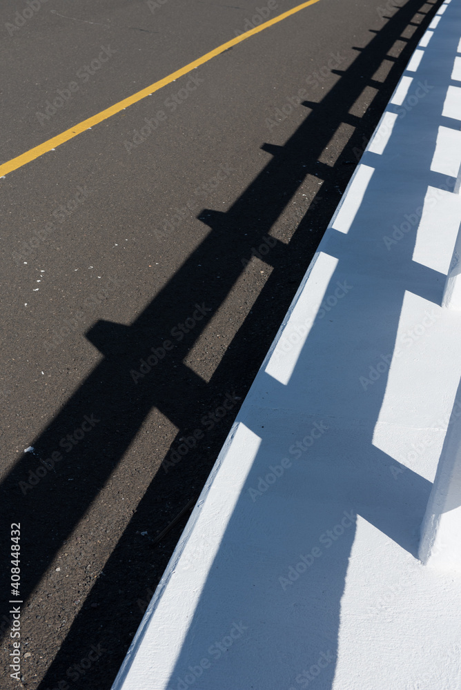 Shadow Of A Bridge Railing On An Asphalt Road