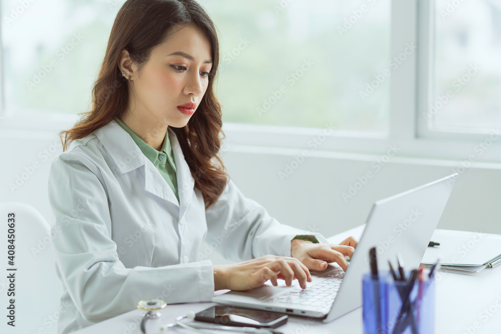 Asian female doctor working with computer at office