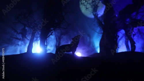 Silhouette of howling wolf against dead forest skyline and full moon. Creative artwork decoration. Selective focus