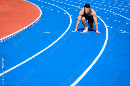 Male athlete on race track is ready to run