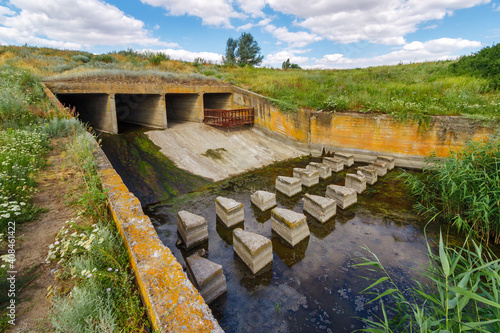 Foto Concrete discharge sluice in earthen dam on small river in countryside