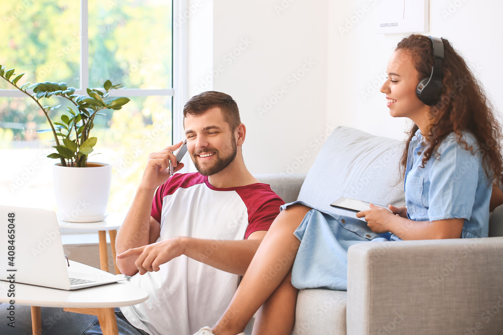 Young couple with gadgets relaxing on sofa at home Young couple with gadgets relaxing on sofa at home