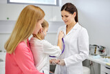 girl playing with stethoscope in hospital, have fun with doctor woman in medical suit, listen to heartbeat of nurse. medicine, healthcare concept