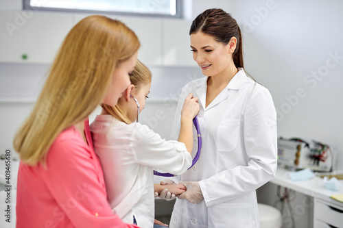 girl playing with stethoscope in hospital  have fun with doctor woman in medical suit  listen to heartbeat of nurse. medicine  healthcare concept
