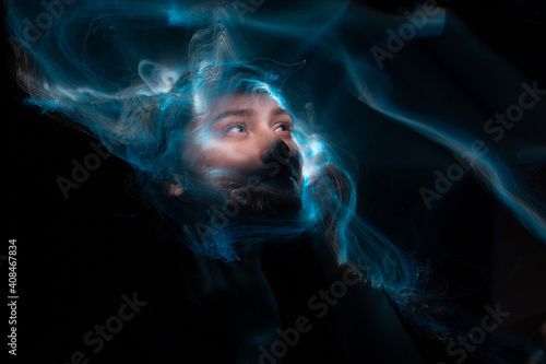 Portrait of young woman amid light painting , Over Black Background. Long exposure photo without photoshop, light drawing at long exposure