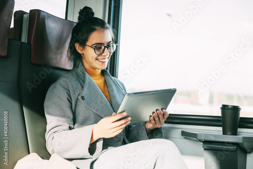 Young girl on the train communicating on the tablet with friends and relatives while traveling on the train