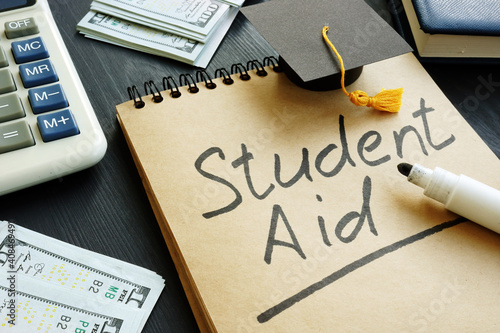 Student aid sign with small graduation cap and money. photo