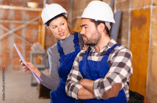 Workers man and woman discuss construction plan. High quality photo